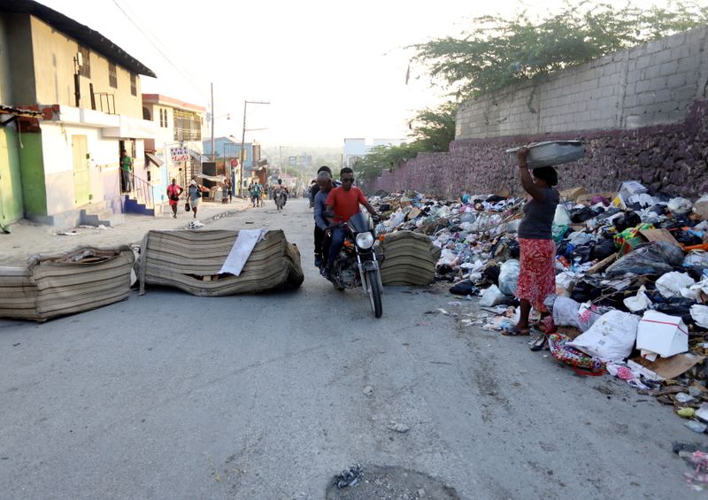 &copy; Reuters. Gente camina y conduce sus motocicletas alrededor de un bloqueo, durante una huelga general para protestar por una creciente ola de secuestros, en Puerto Príncipe, Haití. 18 de octubre de 2021. REUTERS/Ralph Tedy Erol 