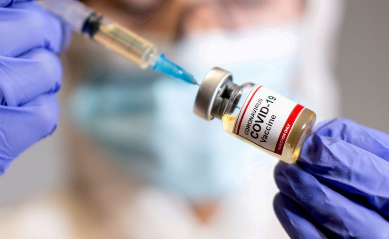 &copy; Reuters. FILE PHOTO: A woman holds a small bottle labeled with a "Coronavirus COVID-19 Vaccine" sticker and a medical syringe in this illustration taken  October 30, 2020. REUTERS/Dado Ruvic//File Photo