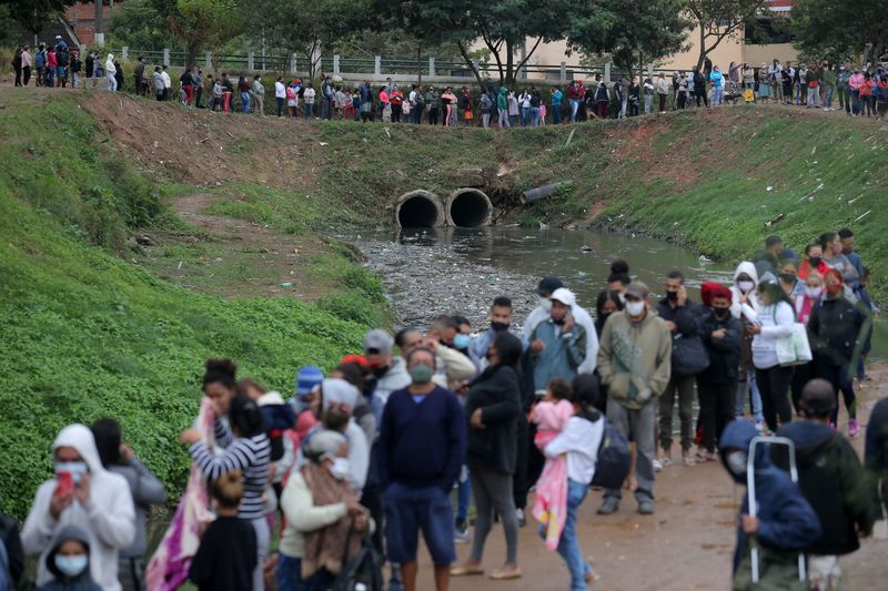 &copy; Reuters. FILE PHOTO: People wait in line to receive food aid distributed by Central Unica das Favelas (CUFA), a Brazilian non-governmental organisation,  amid the coronavirus disease (COVID-19) outbreak at Brasilandia slum in Sao Paulo, Brazil May 13, 2021. REUTER