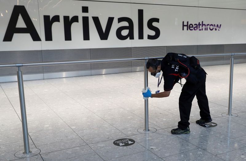 &copy; Reuters. Un trabajador desinfecta una barrera en la zona de llegadas internacionales de la Terminal 5 del aeropuerto londinense de Heathrow