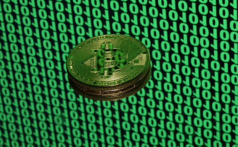 © Reuters. FILE PHOTO: A token of the virtual currency Bitcoin is seen placed on a monitor that displays binary digits in this illustration picture, December 8, 2017. REUTERS/Dado Ruvic/Illustration 