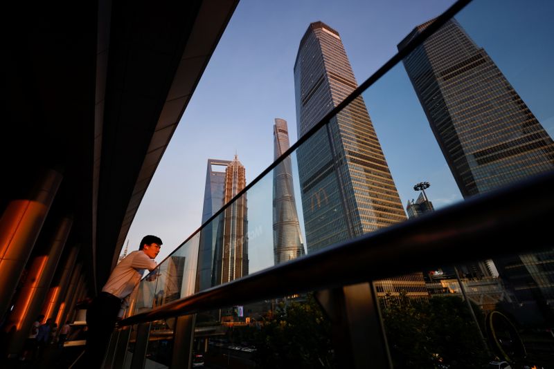 &copy; Reuters. Homem com fones de ouvido no distrito financeiro de Lujiazui durante o pôr do sol em Pudong, Xangai, China, em 13 de julho de 2021. REUTERS/Aly Song