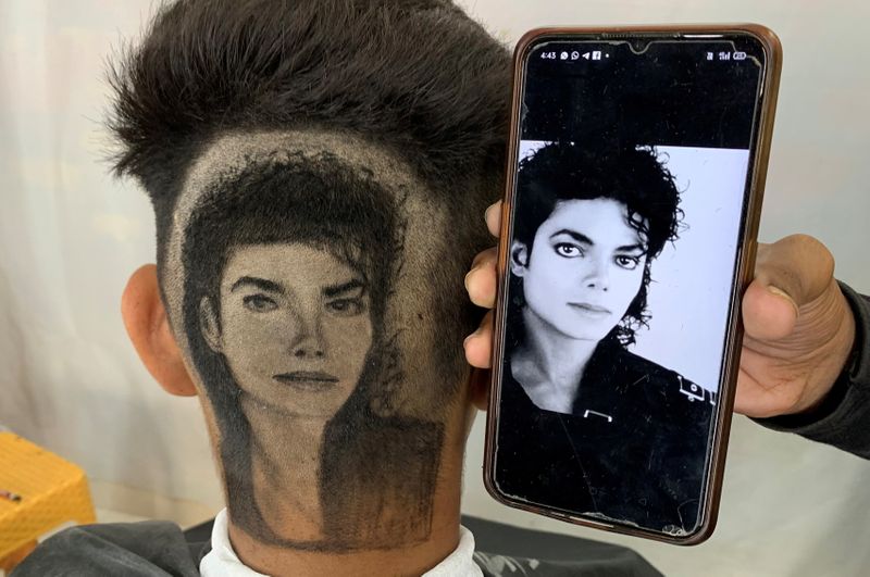 &copy; Reuters. جورويندر سينغ سيدو يعرض صورة مايكل جاكسون بجوار رأس عميل بعدما قص شعره طبقا لصورة في بلدة دابوالي بولاية البنجاب الهندية يوم 11 أكتوبر تشرين 
