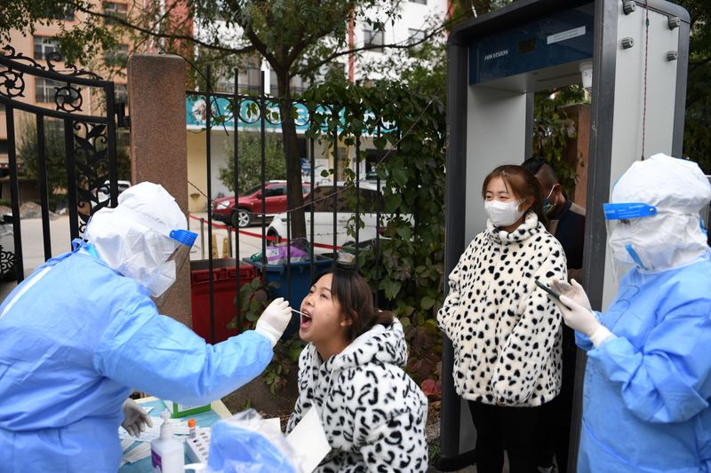 © Reuters. A medical worker in protective suit collects a swab from a resident at a free nucleic acid testing site following new cases of the coronavirus disease (COVID-19), in Lanzhou's Chengguan district, Gansu province, China October 20, 2021. cnsphoto via REUTERS   