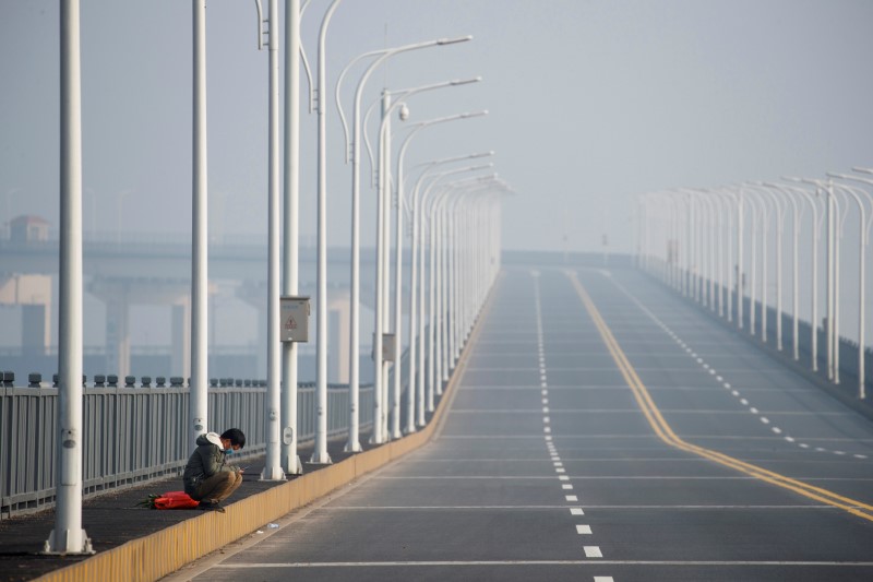 &copy; Reuters. FILE PHOTO: A man who arrived from Hubei province sits near a checkpoint after being refused entry at the Jiujiang Yangtze River Bridge in Jiujiang, Jiangxi province, China, as the country is hit by an outbreak of a new coronavirus, January 31, 2020. REUT
