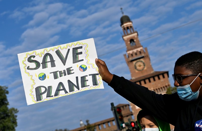 &copy; Reuters. FILE PHOTO: A demonstrator holds up a sign as he attends a Fridays for Future climate strike in Milan, Italy ahead of Glasgow's COP26 meeting. Picture taken on October 1, 2021. REUTERS/Flavio Lo Scalzo/File Photo