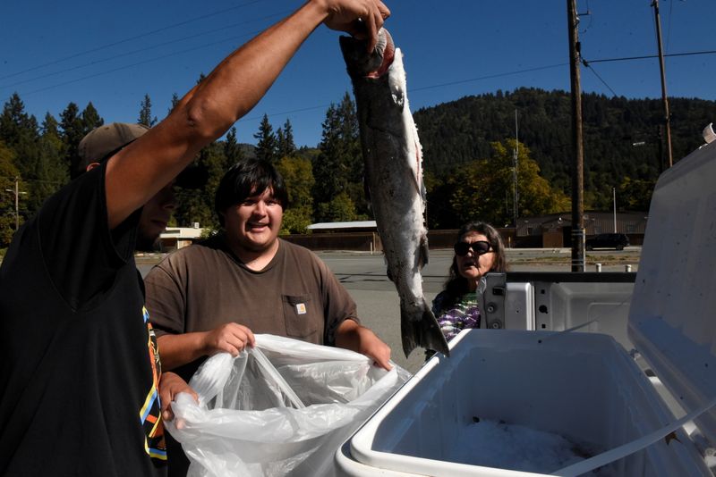&copy; Reuters. AmeriCorps volunteers show a tribal member a salmon caught by the tribe and available for free on the Hoopa Valley Reservation in Hoopa, California, U.S., October 15, 2021.  REUTERS/Stephanie Keith