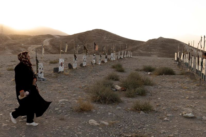 &copy; Reuters. A woman walks past graves at a Hazara cemetery for the Shi'ite community martyrs on a hill on the outskirts of Kabul, Afghanistan October 20, 2021. REUTERS/Jorge Silva