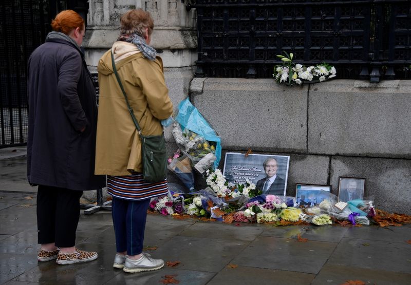 &copy; Reuters. Passers-by view floral tributes to British MP David Amess, who was stabbed to death during a meeting with constituents, placed outside the Houses of Parliament, in London, Britain, October 20, 2021. REUTERS/Toby Melville