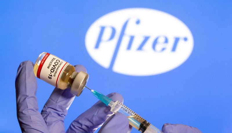 &copy; Reuters. Una persona tiene una fiala etichettata con un adesivo "Vaccino contro il coronavirus COVID-19" e una siringa davanti al logo Pfizer, il 30 ottobre 2020. REUTERS/Dado Ruvic
