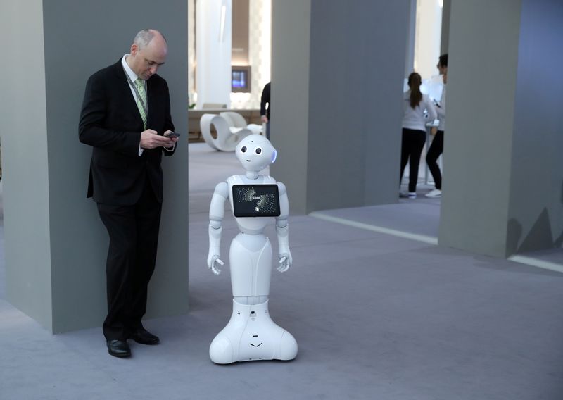&copy; Reuters. FILE PHOTO: A visitor looks at his mobile device next to Pepper the robot during the "Salon International de la Haute Horlogerie" (SIHH) watch fair in Geneva, Switzerland, January 14, 2019. REUTERS/Denis Balibouse/File Photo