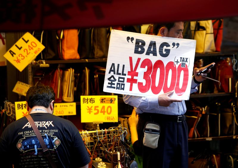 © Reuters. FOTO DE ARCHIVO: Un empleado de una tienda sostiene una pancarta para atraer a los clientes en Tokio, Japón, 16 de mayo de 2018.  REUTERS/Issei Kato/File Photo