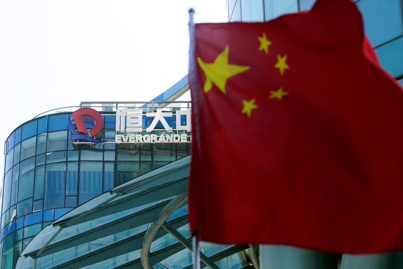&copy; Reuters. A Chinese flag flutters in front of the logo of China Evergrande Group seen on the Evergrande Center in Shanghai, China September 22, 2021. REUTERS/Aly Song  