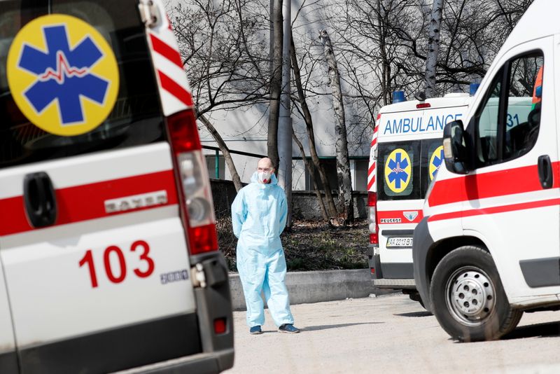 © Reuters. A health worker stands near ambulances with COVID-19 patients as they wait in the queue at a hospital for people infected with coronavirus disease in Kyiv, Ukraine March 30, 2021.  REUTERS/Gleb Garanich