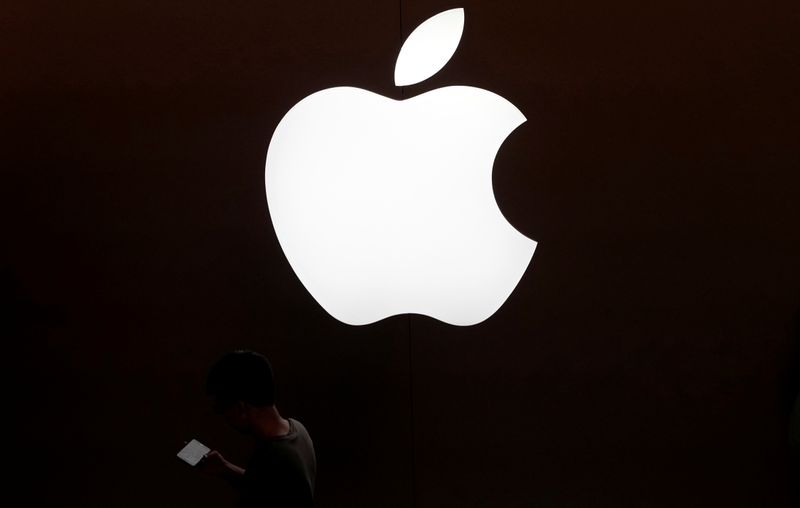 &copy; Reuters. FOTO DE ARCHIVO: Un hombre mira la pantalla de su teléfono móvil frente a un logotipo de Apple fuera de su tienda en Shanghái, China 30 de julio de 2017. REUTERS/Aly Song