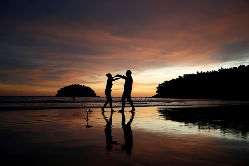 © Reuters. FILE PHOTO: Local residents Stavros from Greece and Valina from Russia dance on an almost empty Kata beach as Phuket reopens to overseas tourists, allowing foreigners fully vaccinated against the coronavirus disease (COVID-19) to visit the resort island without quarantine, in Phuket, Thailand July 1, 2021. REUTERS/Jorge Silva/File Photo