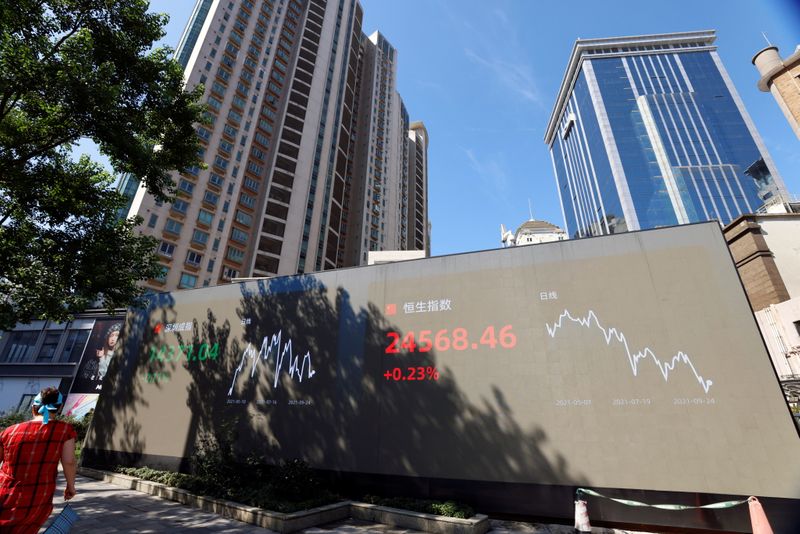 &copy; Reuters. A woman walks by an electronic display showing the Shenzhen and Hang Seng stock indexes, in Shanghai, China, September 24, 2021. REUTERS/Aly Song