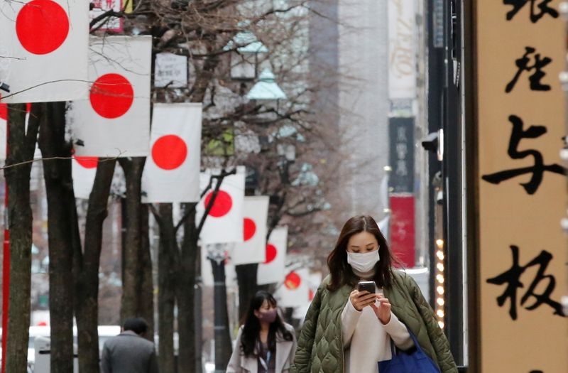 &copy; Reuters. Pedestres usando máscaras protetoras, após o surto de Covid-19, caminham sob as bandeiras nacionais japonesas em um distrito comercial em Tóquio, Japão, 6 de janeiro de 2021. REUTERS/Kim Kyung-Hoon