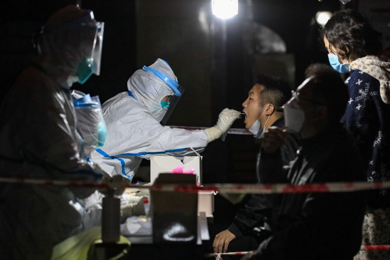 &copy; Reuters. Profissional de saúde usando trajes de proteção coleta amostra para exame de detecção de Covid-19 em Zunyi, na China
21/10/2021 cnsphoto via REUTERS