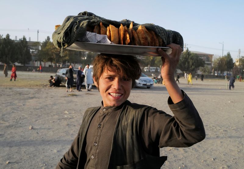 &copy; Reuters. Un vendedor ambulante de comida lleva su bandeja mientras la gente juega al cricket en un parque en Kabul, Afganistán. 22 de octubre de 2021. REUTERS/Zohra Bensemra 