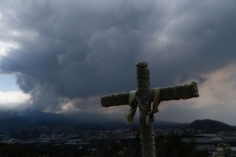 © Reuters. A cross is seen as the Cumbre Vieja volcano continues to erupt in the background at Los Llanos de Aridane, on the Canary Island of La Palma, Spain, October 23, 2021. REUTERS/Susana Vera