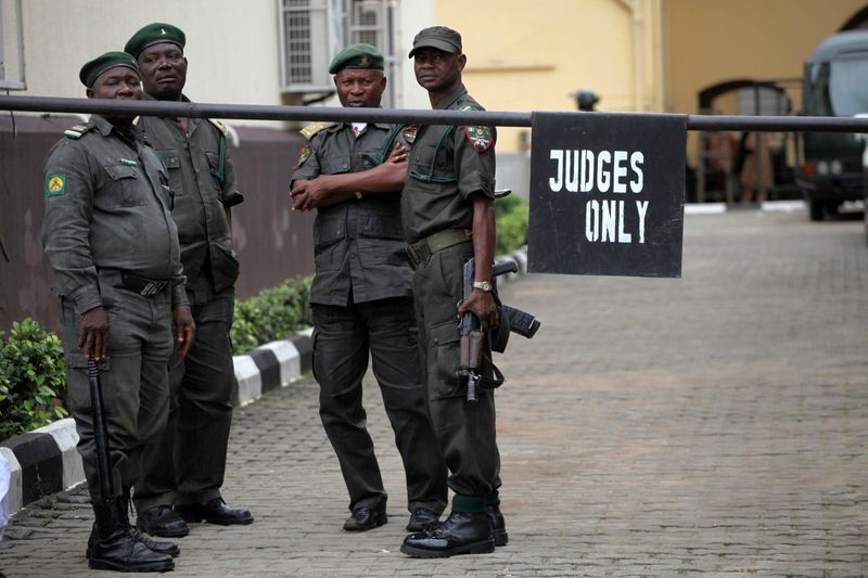 &copy; Reuters. Unos oficiales de seguridad observan a los medios apostados fuera del edificio de la corte suprema en Lagos, Nigeria. FOTO DE ARCHIVO. REUTERS