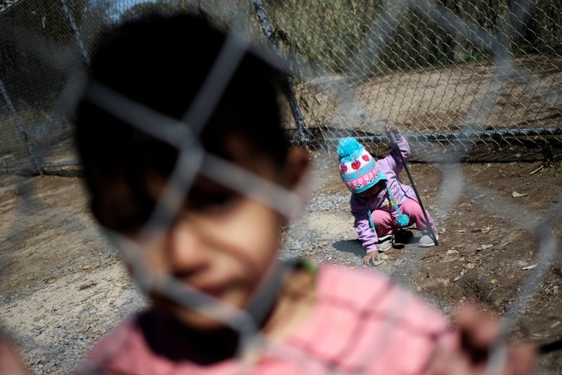&copy; Reuters. Unos niños migrantes que están a la espera de recibir asilo en Estados Unidos miran a través de una valla metálica en un campo para inmigrantes en la ciudad fronteriza de Matamoros, México. FOTO DE ARCHIVO. Febrero, 2021. REUTERS/Daniel Becerril.
