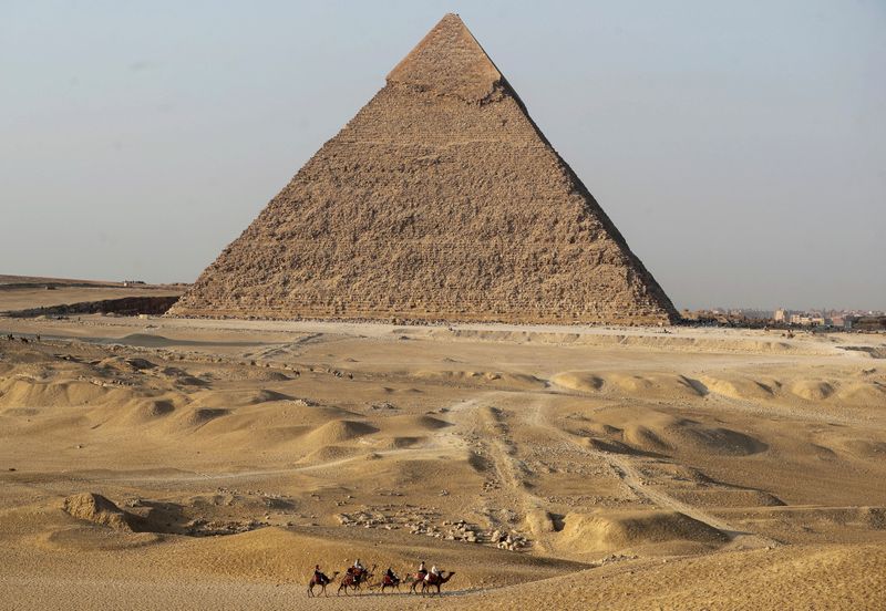 &copy; Reuters. FILE PHOTO: Tourists ride camels in front of the Great Pyramids of Giza, on the outskirt of Cairo, Egypt, October 23, 2021. REUTERS/Mohamed Abd El Ghany