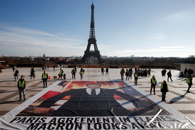 &copy; Reuters. FILE PHOTO: Climate activists stand next to a giant portrait of French President Emmanuel Macron installed on the ground at Trocadero square in front of the Eiffel tower to mark the fifth anniversary of the 2015 United Nations Paris Agreement on climate c