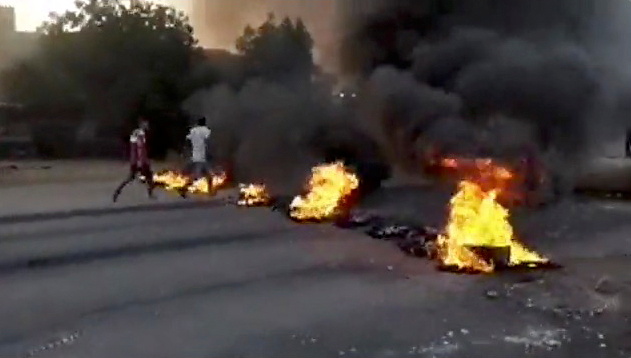 &copy; Reuters. أشخاص يمشون بجوار أشياء محترقة ملقاة في شوارع بالخرطوم وسط تقارير عن انقلاب يوم الاثنين. صورة لرويترز مأخوذة من مقطع فيديو تم الحصول عليه عب