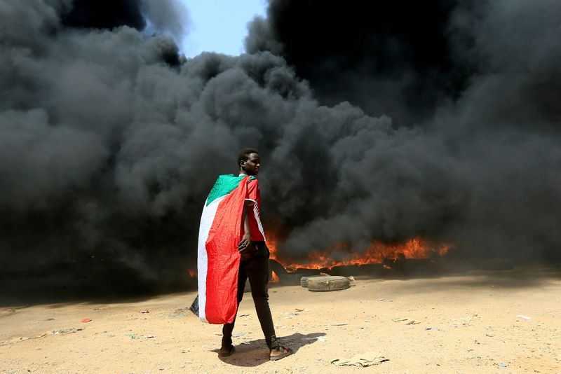&copy; Reuters. FILE PHOTO: A person wearing a Sudan's flag stand in front of a burning pile of tyres during a protest  against prospect of military rule in Khartoum, Sudan October 21, 2021. REUTERS/Mohamed Nureldin Abdallah//File Photo
