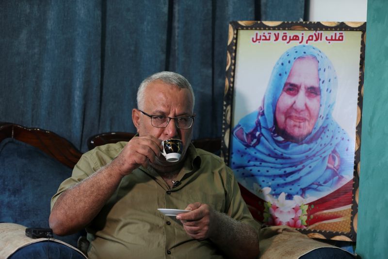 © Reuters. الفلسطيني منير حمو يجلس بالقرب من صورة والدته في منزل أسرته في غزة يوم 19 أكتوبر 2021. تصوير: إبراهيم أبو مصطفى - رويترز.