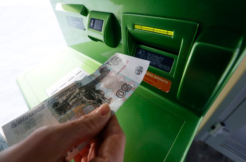 &copy; Reuters. A woman inserts a 50-rouble banknote into an ATM bank machine at a branch of Sberbank in Krasnoyarsk, Siberia, January 27, 2015. Russia's rouble strengthened by over 1 percent against both the dollar and euro in early trade on Tuesday, bouncing back after