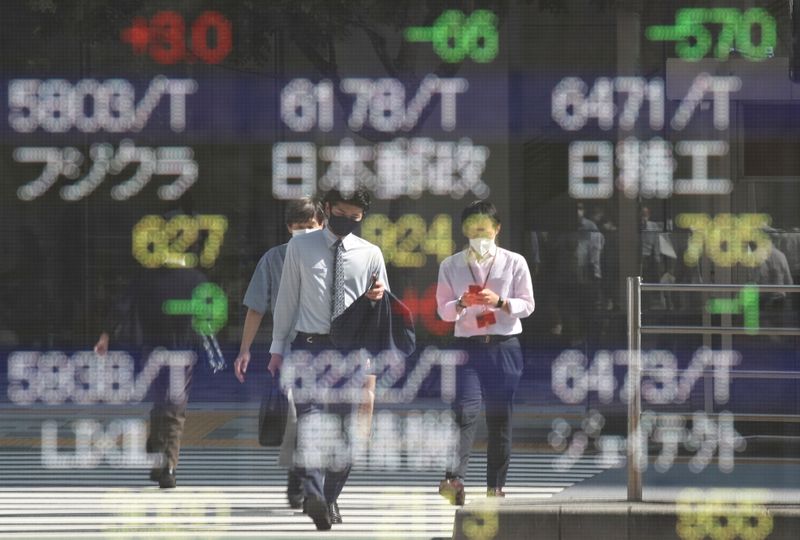 &copy; Reuters. صورة بعض المارة تنعكس على سطح لوحة إلكترونية تعرض حركة المؤشرات خارج بورصة طوكيو في 5 أكتوبر تشرين الأول 2021. رويترز