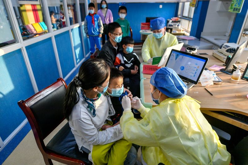 &copy; Reuters.  中国当局によると、１０月２６日に新たに５０人の新型コロナウイルスの市中感染が確認された。写真は２６日、浙江省湖州市の病院でワクチン接種を受ける子ども（２０２１年　ロイタ
