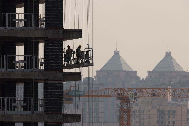 &copy; Reuters. FOTO DE ARCHIVO: Unos hombres trabajan en las obras de construcción de un rascacielos en Pekín, China, el 18 de octubre de 2021.   REUTERS/Thomas Peter