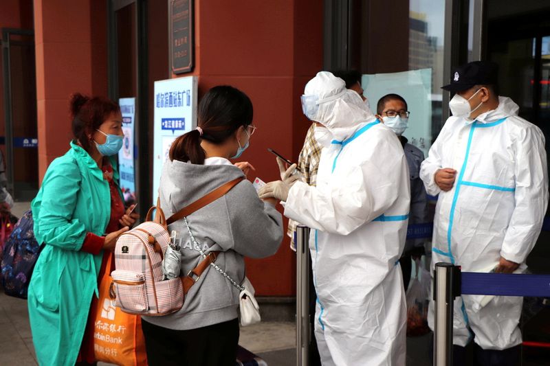 &copy; Reuters. Staff members in protective suits check proof of negative test results for travellers at an entrance to the Harbin West Railway Station following new local cases of the coronavirus disease (COVID-19) in Harbin, Heilongjiang province, China September 22, 2