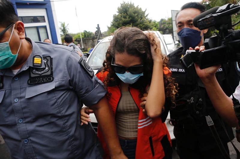 &copy; Reuters. Heather Mack, an American woman jailed in 2015 with her boyfriend after being found guilty of playing a role for murdering her mother and stuffing the remains in a suitcase, is escorted by immigration officers after being released from Kerobokan Prison, a