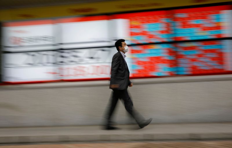 &copy; Reuters. FILE PHOTO: A man wearing a protective face mask, following the coronavirus disease (COVID-19) outbreak, walks in front of a stock quotation board outside a brokerage in Tokyo, Japan, May 18, 2020. REUTERS/Kim Kyung-Hoon