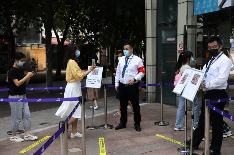&copy; Reuters. A woman shows her health status on a phone to a security guard, at an entrance of a shopping mall in Beijing, China August 23, 2021. REUTERS/Tingshu Wang