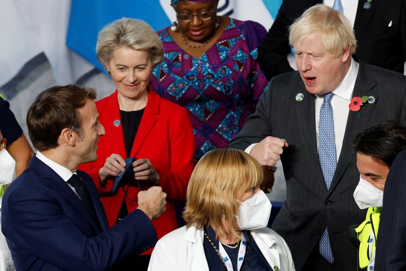 &copy; Reuters. El presidente de Francia, Emmanuel Macron (izq), y el primer ministro británico, Boris Johnson, gesticulan con los puños durante la foto de familia de la cumbre de líderes del G-20 en Roma, Italia. 30 octubre 2021. Ludovic Marin/Pool vía Reuters