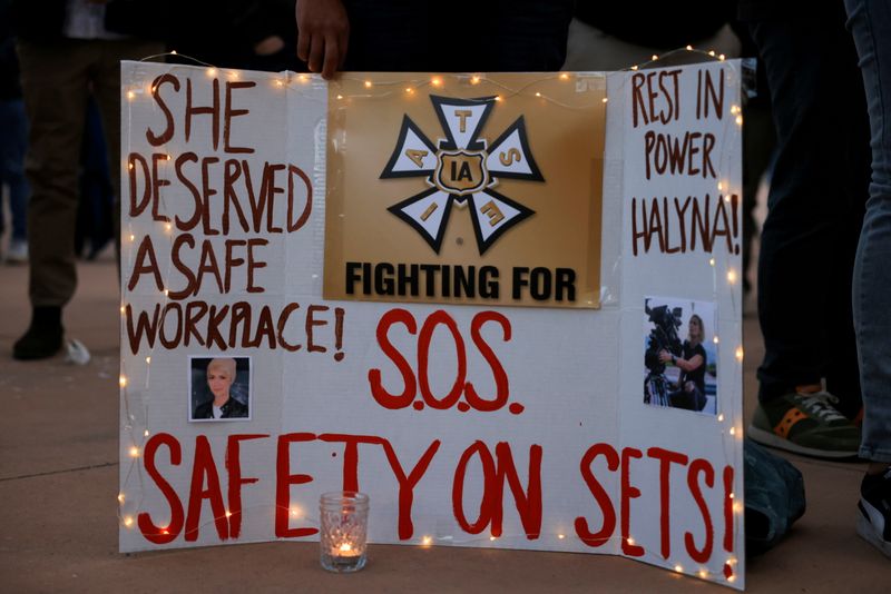 © Reuters. FILE PHOTO: A woman displays a sign calling for workplace safety at a vigil for cinematographer Halyna Hutchins, who died after being shot by Alec Baldwin on the set of his movie 