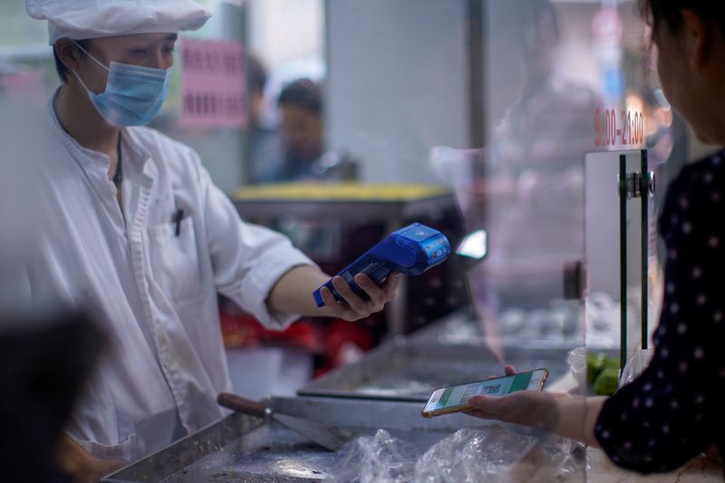 &copy; Reuters. FILE PHOTO: A woman gets her phone's QR code of the digital payment services scanned at a food shop, following the coronavirus disease (COVID-19) outbreak, in Shanghai, China October 10, 2020. REUTERS/Aly Song