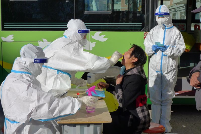 © Reuters. A medical worker in protective suit collects a swab during the fifth round of mass nucleic acid testing for residents of Aihui district following new cases of the coronavirus disease (COVID-19) in Heihe, Heilongjiang province, China October 31, 2021. China Daily via REUTERS