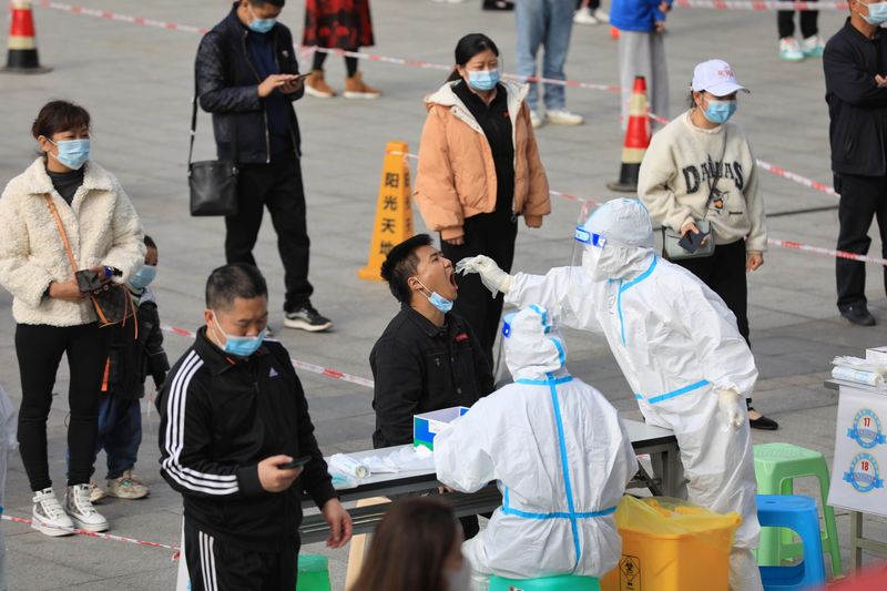 &copy; Reuters. A medical worker in protective suit collects a swab from a man during a mass nucleic acid testing in Huichuan district following new cases of the coronavirus disease (COVID-19) in Zunyi, Guizhou province, China October 23, 2021. cnsphoto via REUTERS   