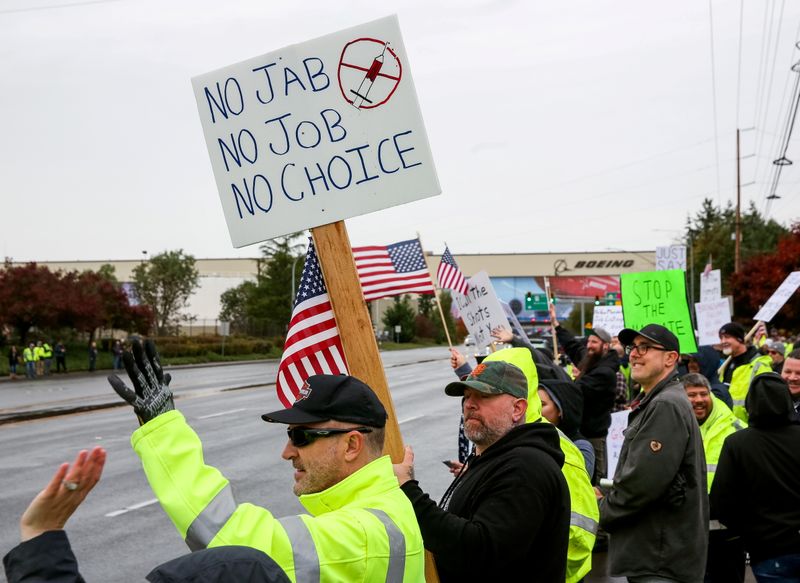 &copy; Reuters. FILE PHOTO: Boeing employees and others line the street with signs and American flags as they protest the company's coronavirus disease (COVID-19) vaccine mandate, outside the Boeing facility in Everett, Washington, October 15, 2021.  REUTERS/Lindsey Wass