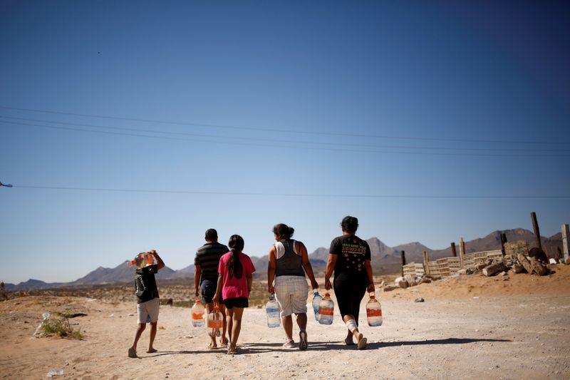 © Reuters. Foto de archivo. Personas llevando botellas de agua potable entregadas por estudiantes de secundaria en apoyo de vecindarios con falta de agua, en Ciudad Juárez, México, 28 de mayo de 2021. REUTERS / José Luis González 