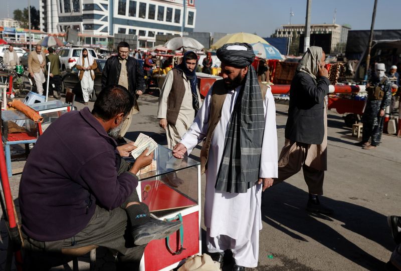 &copy; Reuters. FILE PHOTO: An Afghan currency exchange dealer checks banknotes in front of a man at the market in Kabul, Afghanistan October 24, 2021. REUTERS/Stringer/File Photo