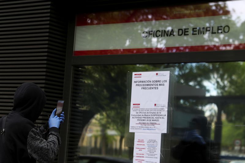 &copy; Reuters. FILE PHOTO: A man wearing protective gloves takes pictures of an information board outside a government job center closed for the public during the coronavirus disease (COVID-19) outbreak in Madrid, Spain, April 28, 2020. REUTERS/Susana Vera