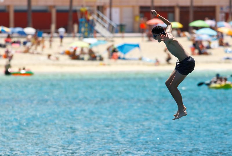 &copy; Reuters. FILE PHOTO: A tourist jumps into the sea on the Amadores beach, amid the outbreak of the coronavirus disease (COVID-19) in the south of the island of Gran Canaria, Spain, August 3, 2021. REUTERS/Borja Suarez/File Photo